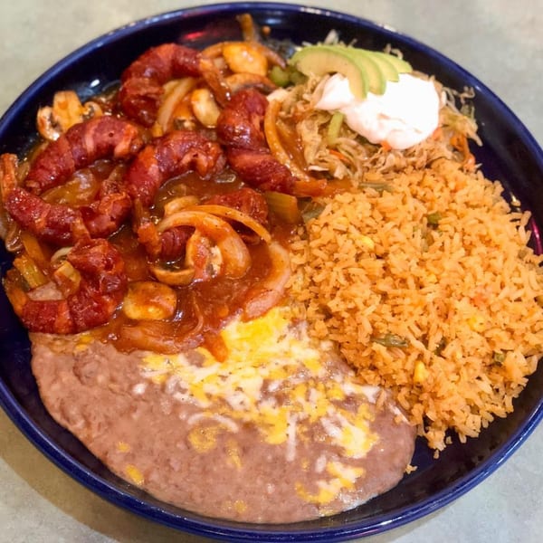 Bacon-wrapped shrimp with onions and mushrooms, served with Mexican rice, refried beans, and avocado.
